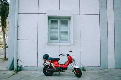 red-motor-scooter-parked-beside-white-concrete-building-2044876